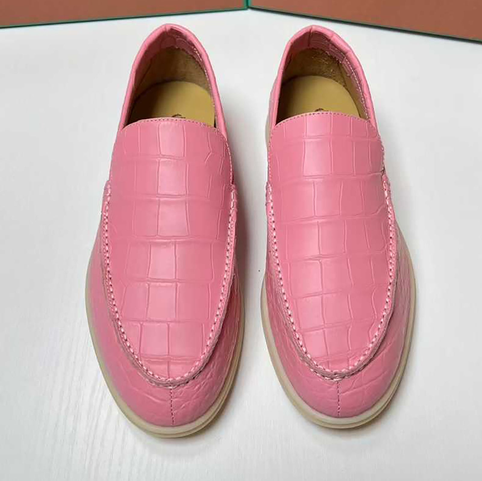 Pair of pink loafers with a textured pattern on a white surface