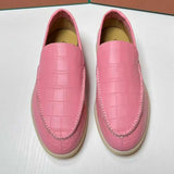 Pair of pink loafers with a textured pattern on a white surface