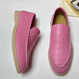 Pink loafers with a textured pattern on a white surface
